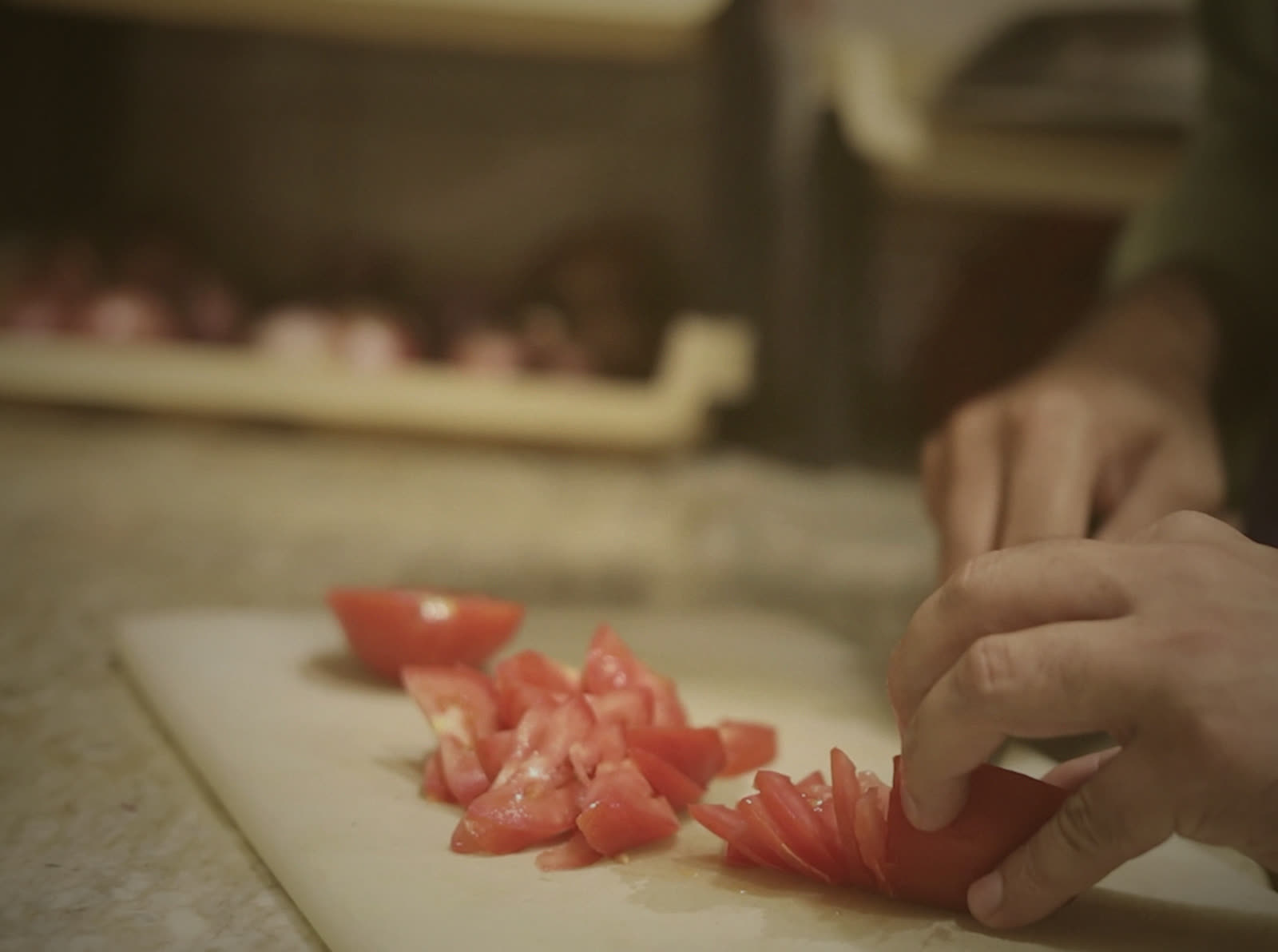Hands chopping tomatoes on a board in the home kitchen
