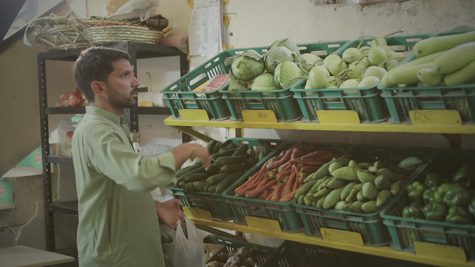 Waqas choosing vegetables from green crates at the sabzi mandi